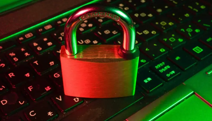 Un cadenas sur un clavier d'ordinateur, symbolisant la **sécurité informatique**. La lumière rouge et verte crée une ambiance de protection numérique.