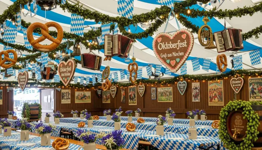Wystrój namiotu Oktoberfest: obrusy w kratę, precle, akordeony, serca z piernika i dekoracje.