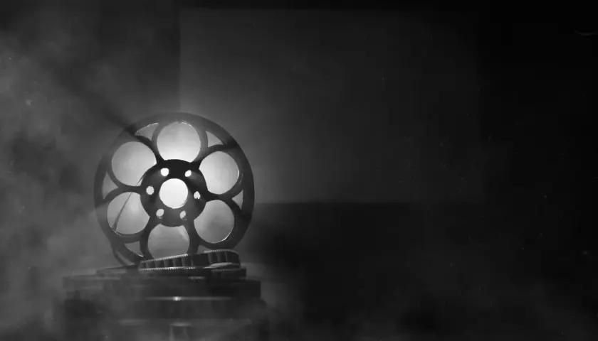 Stara taśma filmowa mk2, oświetlona od tyłu, unosi się w dymie, tworząc magiczną atmosferę kina.