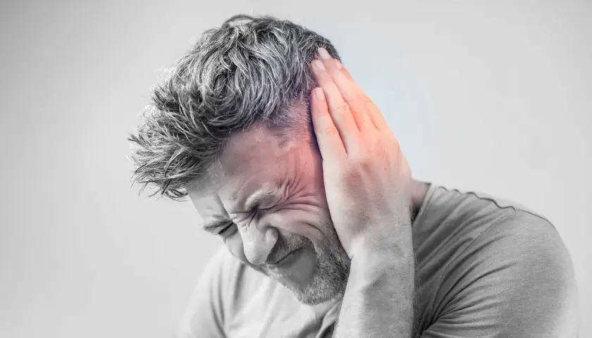 Hombre con mano en la oreja, sufriendo un intenso zumbido oido.