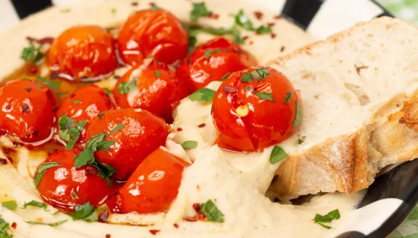 Cremiger veganer Tomatenaufstrich mit gerösteten Kirschtomaten, Kräutern und Brot.