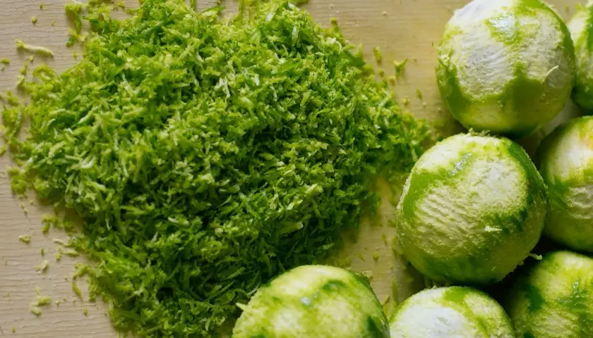 Świeżo starta skórka z limonek, idealna do domowego kordiału. Obok leżą obrane limonki.