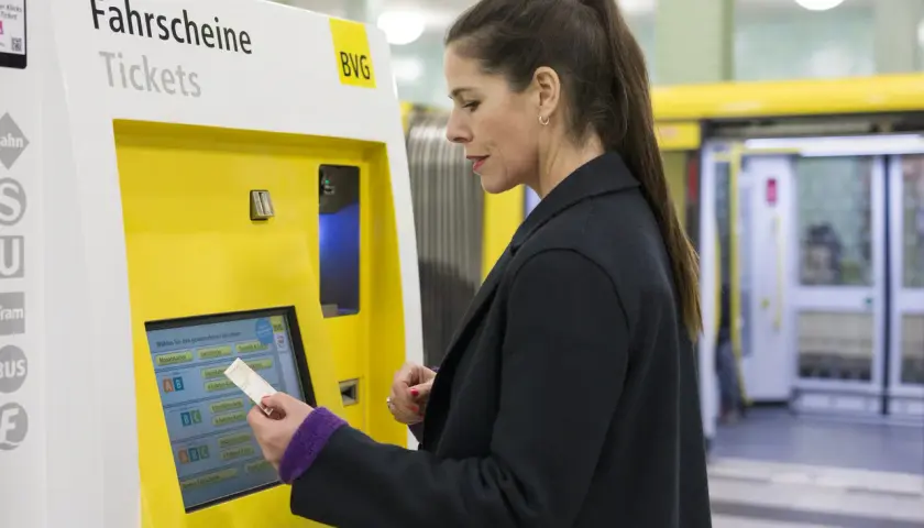 Frau kauft am Automaten ein Ticket. Die Bedeutung von SPNV (Schienenpersonennahverkehr) wird hier durch den Kauf eines Fahrscheins für die Fahrt mit Bus oder Bahn deutlich.