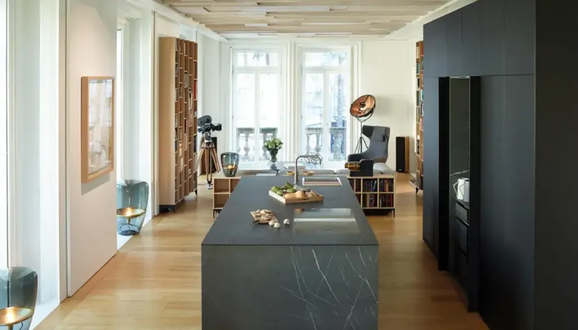 Cucina moderna con isola in pietra, parquet chiaro e dettagli in cementine.