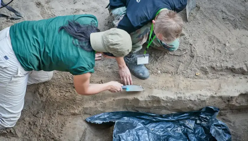 Archeolodzy prowadzą ekshumację, ostrożnie badając warstwy ziemi.