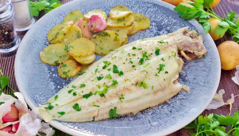 Delicioso lenguado al horno con patatas panadera y ajo. Un plato principal ligero y sabroso.