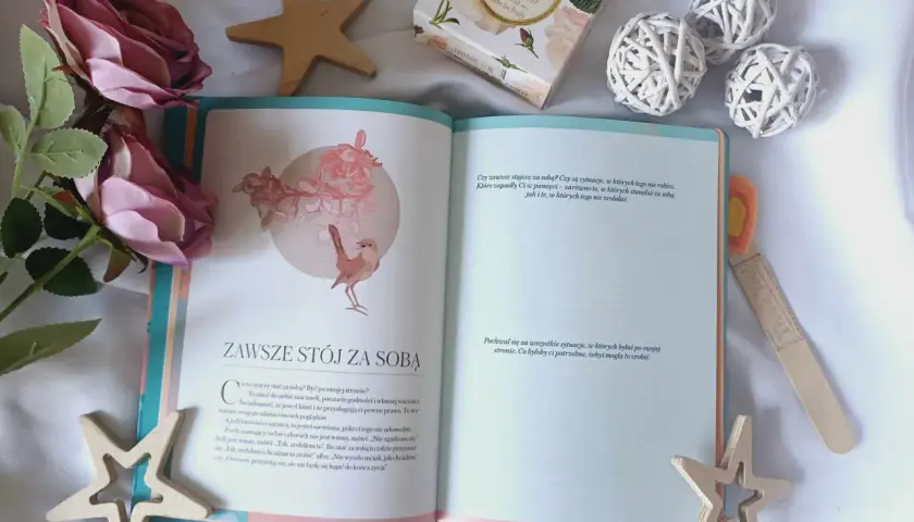 Otwarta książka z cytatem "Zawsze stój za sobą" i dekoracjami. Inspiracja, jak naprawić swoje życie, zaczyna się od wiary w siebie.
