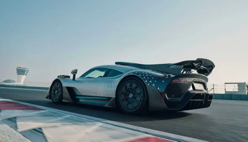 Srebrny Mercedes-AMG ONE z charakterystycznym wzorem gwiazdek na karoserii pędzi po torze wyścigowym.