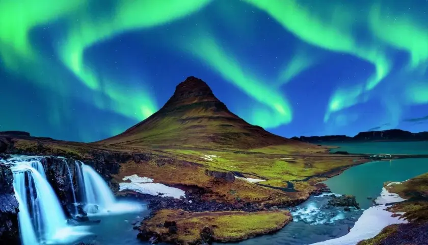 Góra Kirkjufell i wodospad pod zorzą polarną na Islandii.