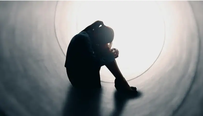 Silhouette di una persona rannicchiata in un tunnel, simbolo di solitudine e mancanza di affetto.