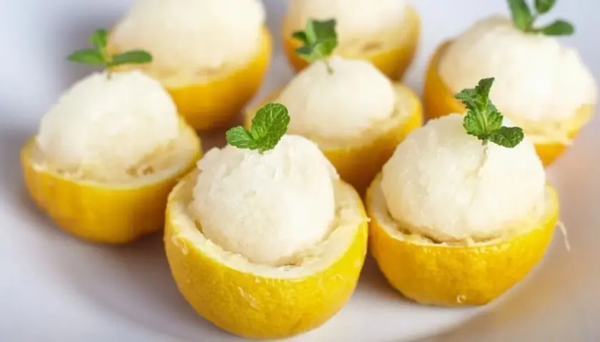 Sorbet cytrynowy w połówkach cytryn, udekorowany listkami mięty.