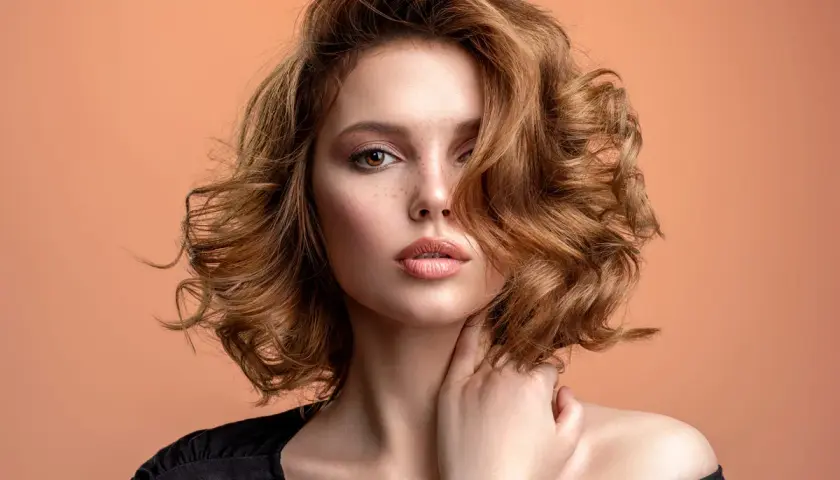 Mujer con pelo ondulado color cobre, un estilo que marca la tendencia pelo 2026.