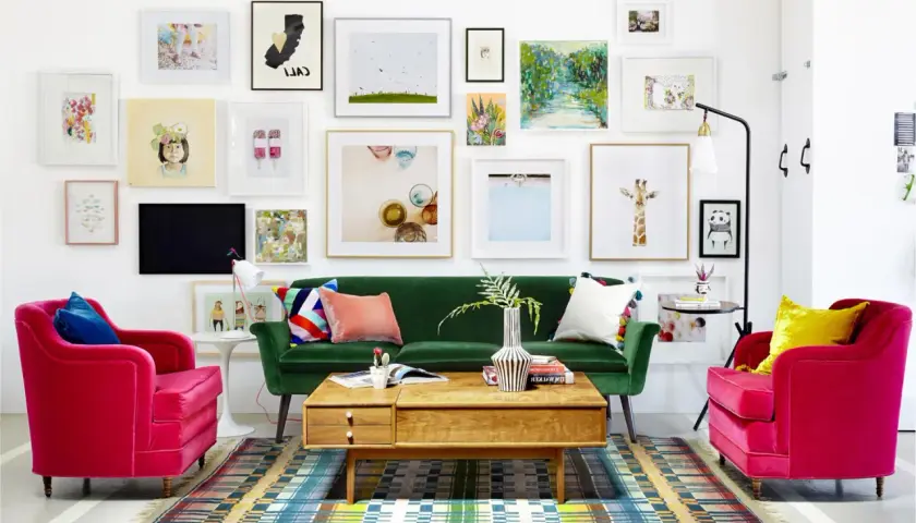 Salon w stylu new eklektyzm: zielona sofa, fuksjowe fotele, kolorowy dywan i ściana pełna różnorodnych obrazów.