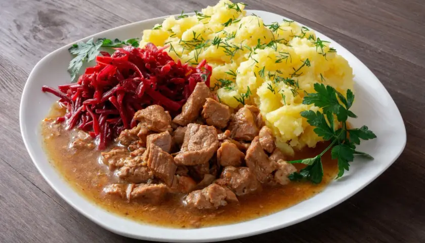 Pyszny gulasz z łopatki podany z ziemniakami i buraczkami.