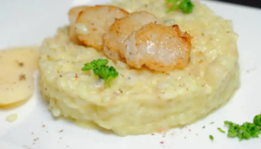 Un crémeux risotto poire gorgonzola, garni de Saint-Jacques poêlées et d'une touche de persil frais.