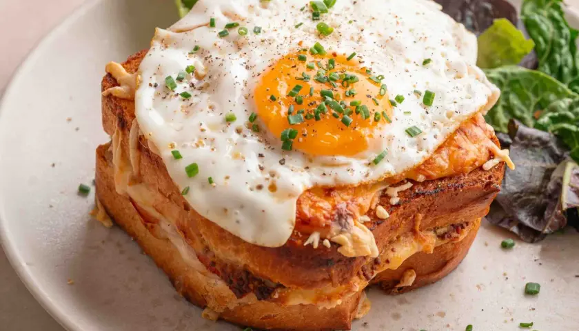 Un délicieux croque madame recette, avec un œuf au plat coulant, du fromage fondant et une salade verte. Un plat gourmand à souhait.