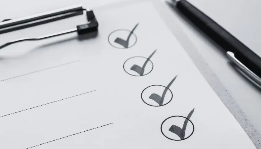 Liste de contrôle pour une visite maison : un stylo noir et un presse-papiers sur une feuille avec des cases cochées.