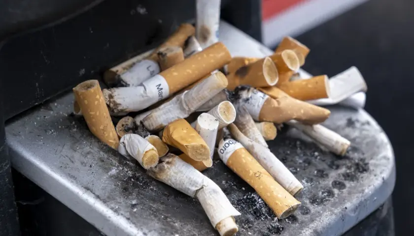 Kupa niedopałków papierosów w popielniczce. Zastanawiasz się, ile kosztują papierosy we Francji?