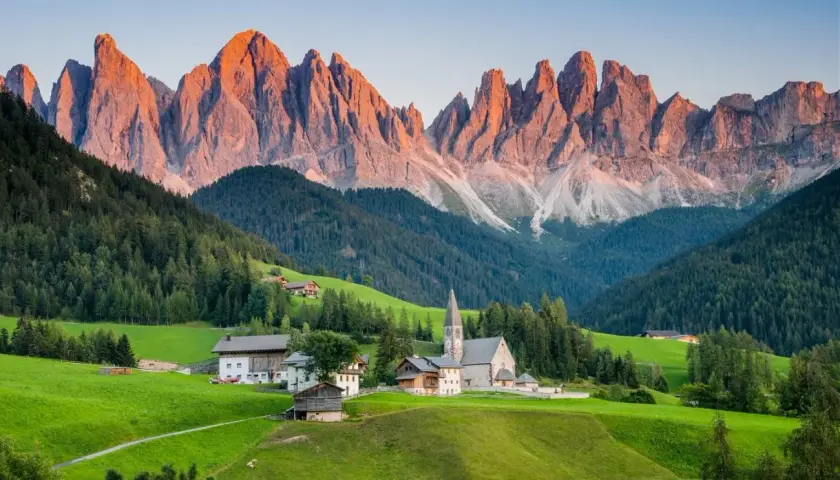 A picturesque village nestled in a valley, with the jagged peaks of the Dolomites catching the golden light, a stark contrast to the gentler slopes of the Alps.