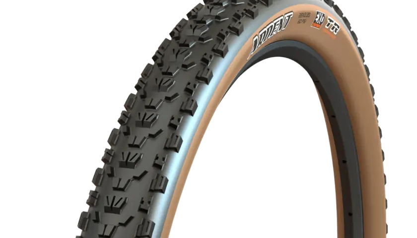 A close-up of a Maxxis Ardent tire with tan sidewalls, ready for a trail review. Its aggressive tread promises grip.