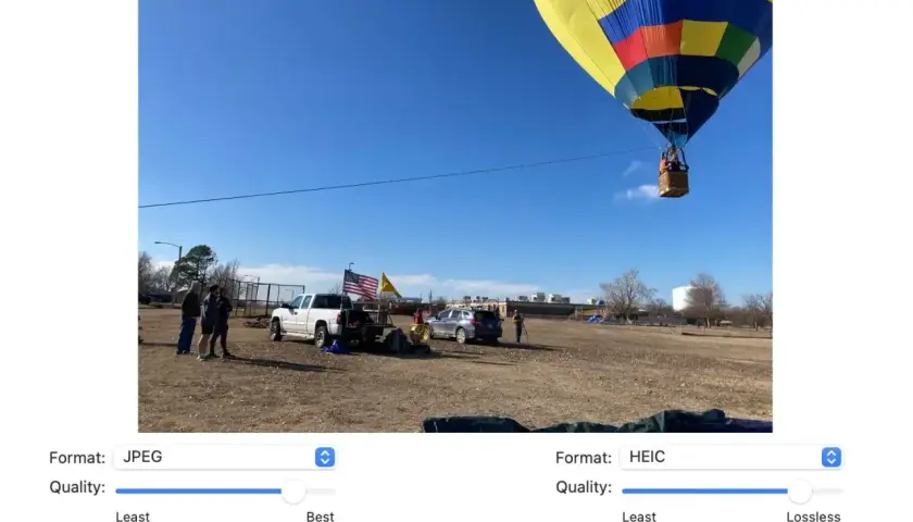 Balon na gorącym powietrzu wznosi się na błękitnym niebie. Na ziemi stoją ludzie, samochody i amerykańska flaga. Obraz porównuje formaty HEIC i JPG.