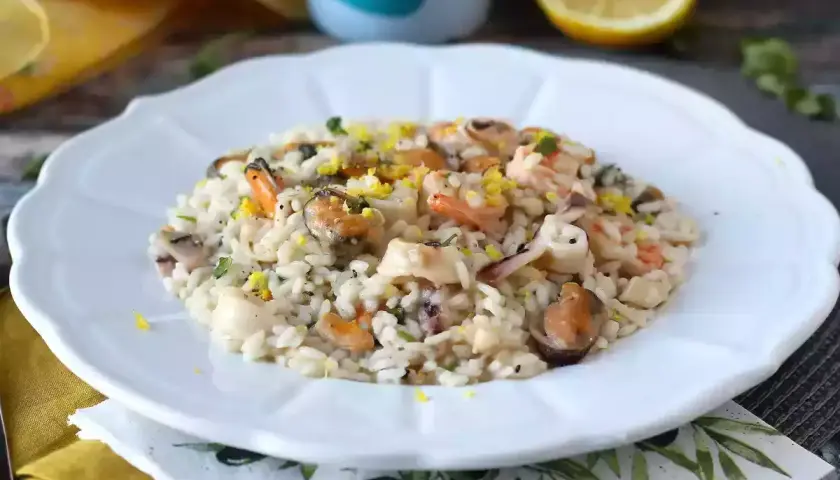 Un délicieux risotto aux fruits de mer, garni de zestes de citron et de persil. Un plat savoureux qui rappelle la mer.