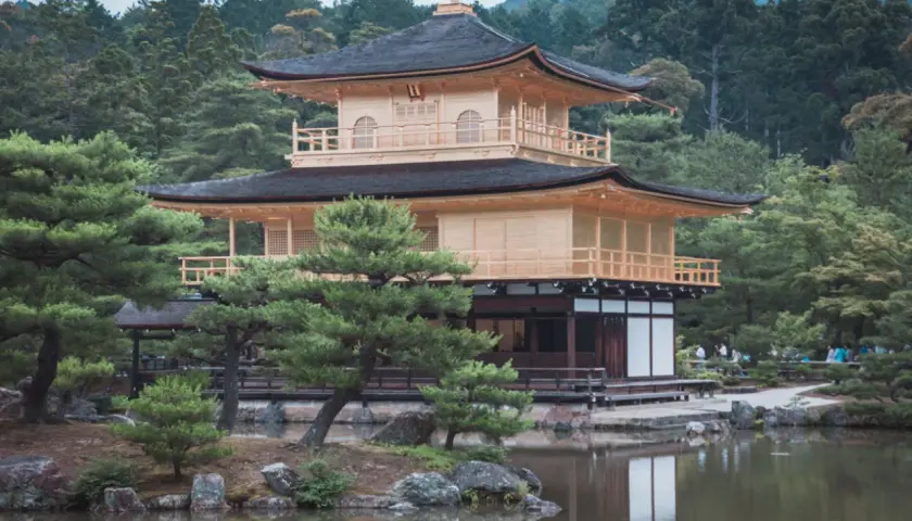 Złoty Pawilon Kinkaku-ji w Kioto, otoczony zielenią i odbijający się w stawie.
