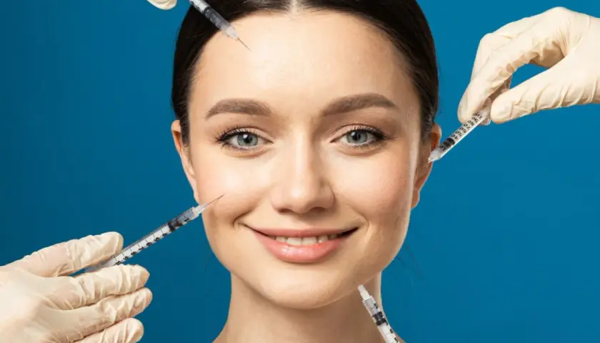 Ansiktsbehandling med botox och fillers. En kvinna ler medan flera sprutor närmar sig hennes ansikte för injektioner.