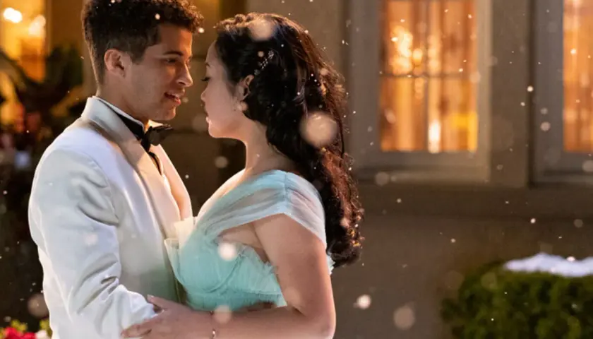Jordan Fisher dans une scène romantique de films et séries tv. Il danse avec une jeune femme en robe bleu pâle, sous une pluie de flocons.