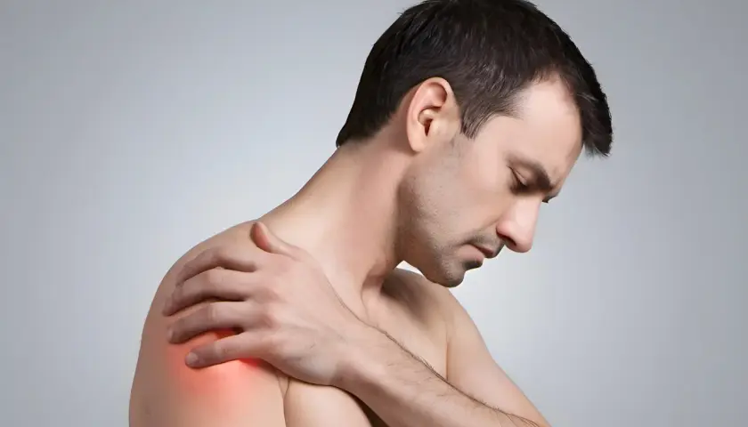 Mann mit schmerzender Schulter, die auf eine Frozen Shoulder hindeutet. Osteopathie kann hier Linderung verschaffen.