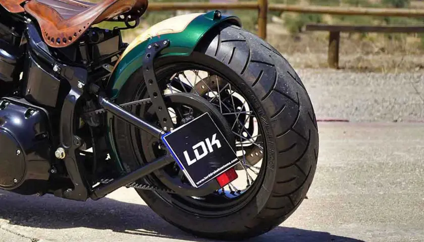 Detalle de moto customizada con asiento de cuero y guardabarros verde. La matrícula, con las medidas adecuadas, muestra el logo LDK.