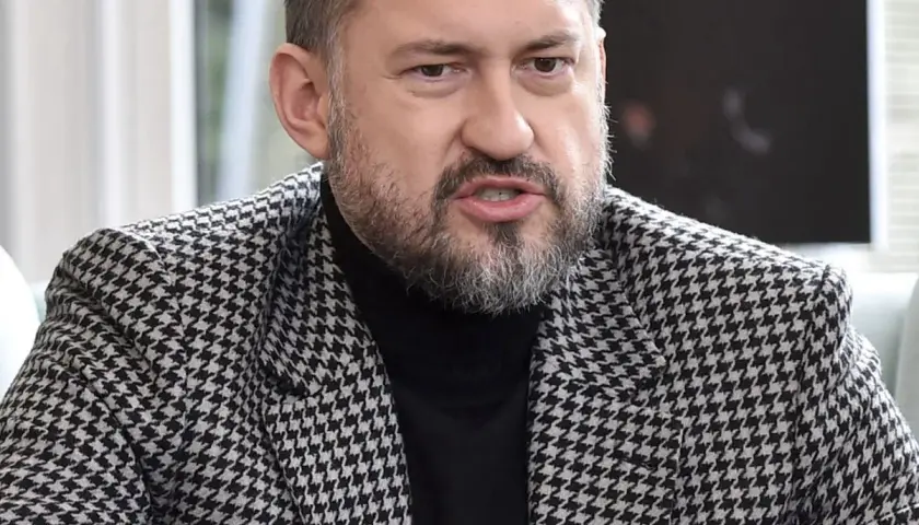 Marcin Prokop w czarnej golfie i marynarce w pepitkę.