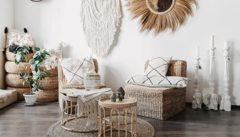 Wnętrze w stylu boho: plecione meble, makrama, lustro z trawy, poduszki z geometrycznymi wzorami i rośliny tworzą przytulną atmosferę.