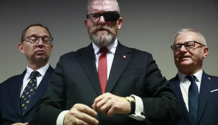 Trzech mężczyzn w garniturach. Lider z opaską na oku, zastanawia się, czy Konfederacja Korony Polskiej planuje samodzielny start w wyborach.
