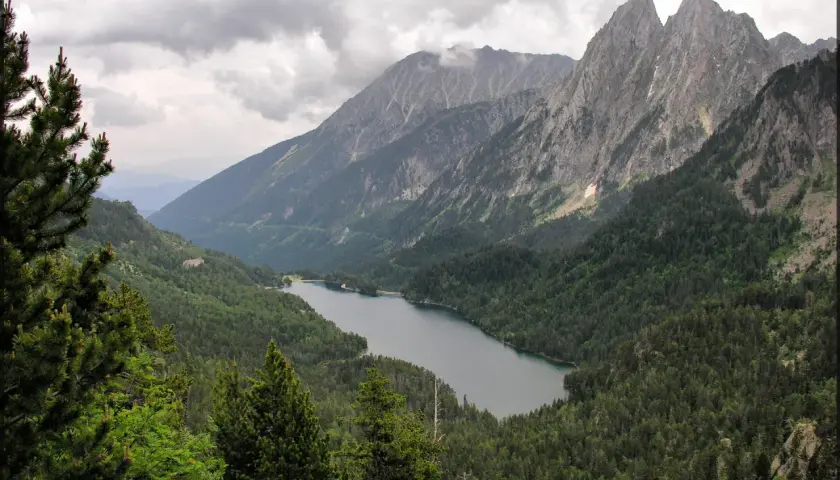 Paisaje montañoso con un lago sereno rodeado de bosques frondosos, ideal para explorar rutas desde Espot.