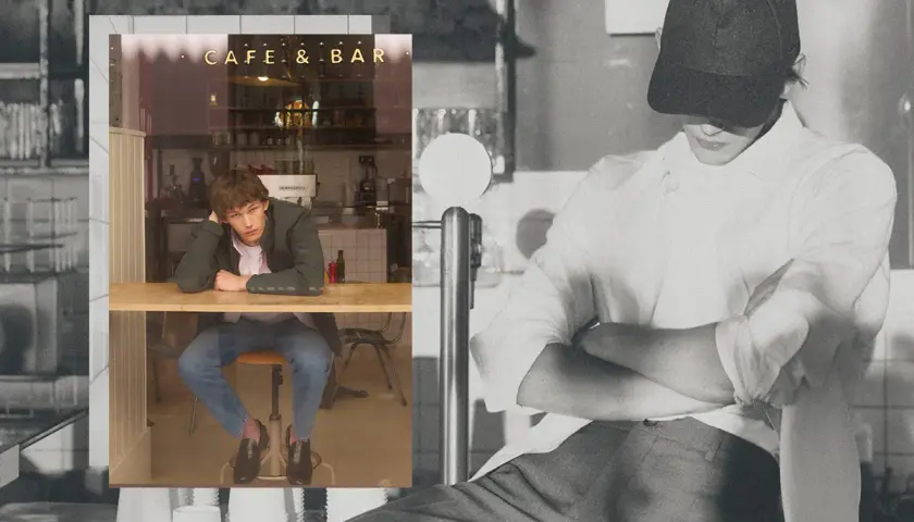 Un joven con un armario cápsula hombre, sentado en un café, reflexiona.