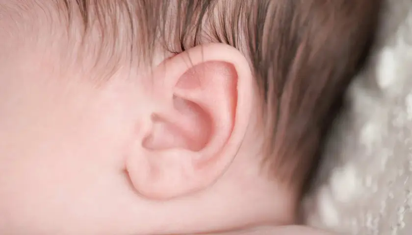 Primo piano dell'orecchio di un neonato, un dettaglio delicato che può essere interessato da otite nei bambini.