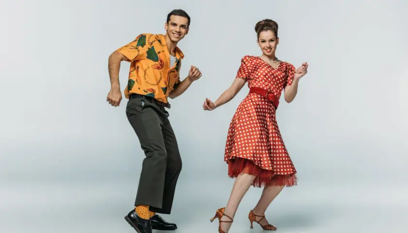 Coppia in abiti vintage che esegue boogie woogie passi e figure con gioia.