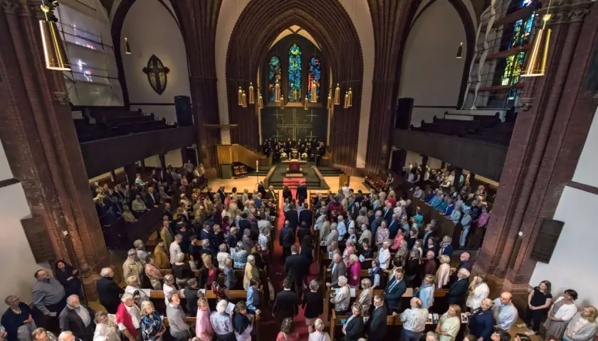 Menschen versammeln sich in einer Kirche für einen evangelischen Gottesdienst. Die evang. Gottesdienstordnung wird vorbereitet.