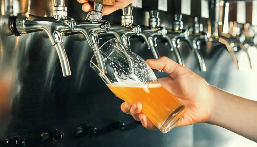 Main d'un barman servant une bière blonde pétillante. Pour comment augmenter la dureté de l'eau, on pourrait ajouter des minéraux.