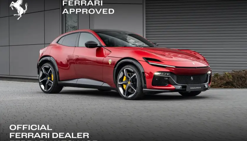 Czerwony Ferrari Purosangue, luksusowy SUV, prezentuje się dumnie przed budynkiem dealera.