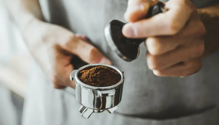 Barista tamped den frisch gemahlenen Kaffee für einen perfekten Kaffee shot.