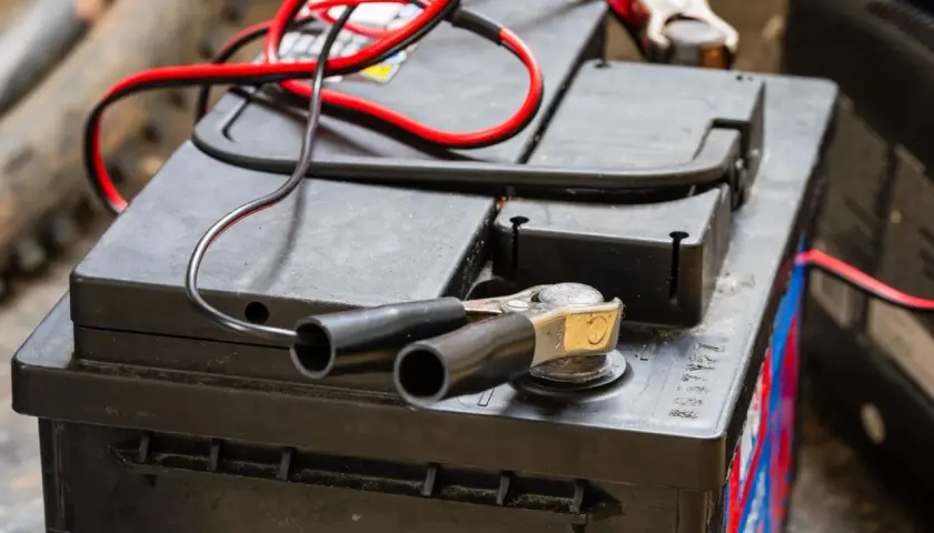 Pinces rouges et noires connectées à une batterie, prêt à savoir comment recharger les batteries d'un camping-car.