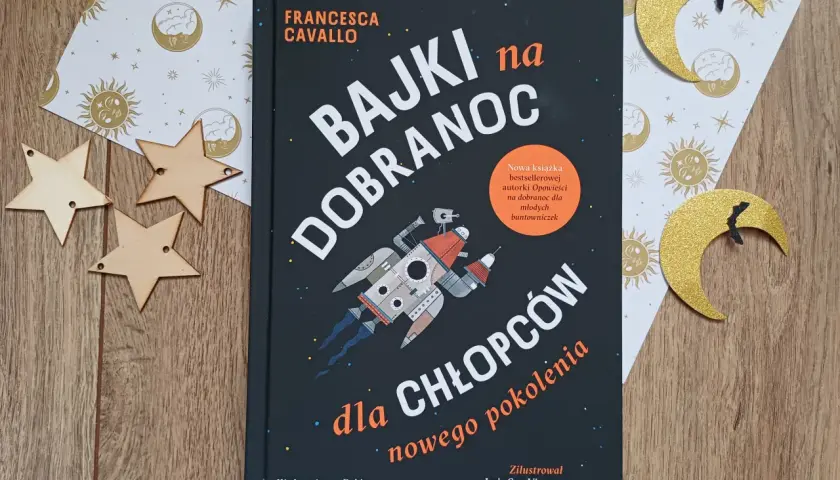 Książka "Bajki na dobranoc dla chłopców nowego pokolenia" z rakietą na okładce, otoczona złotymi gwiazdkami i księżycami.