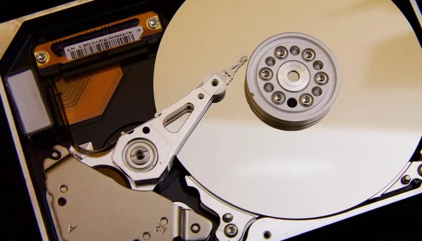 Vue rapprochée de l'intérieur d'un disque dur de PC, montrant le plateau, la tête de lecture/écriture et le moteur. L'emplacement du disque dur PC est essentiel pour le stockage des données.