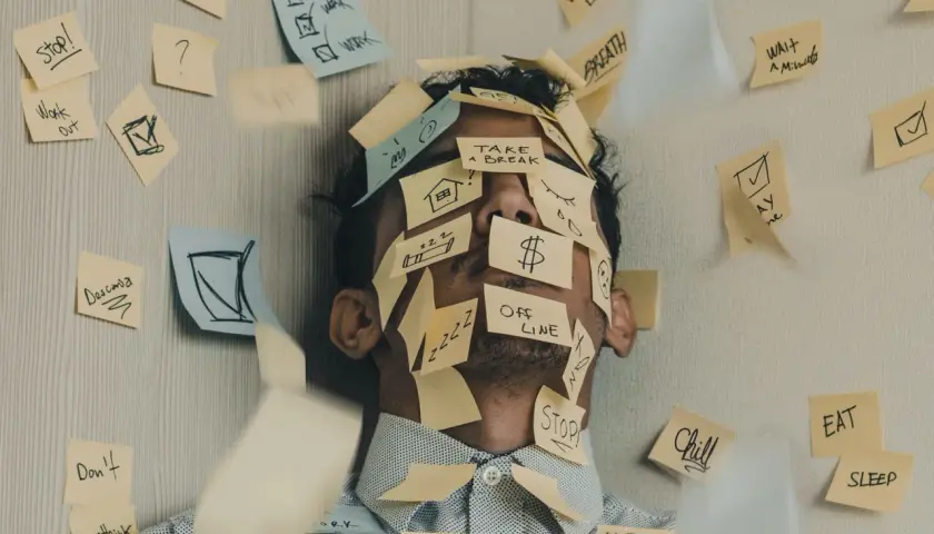 Twarz mężczyzny zasłonięta karteczkami z przypomnieniami: "Stop!", "Work", "Take a break", "Offline". To chyba właśnie jest presja, co to znaczy?