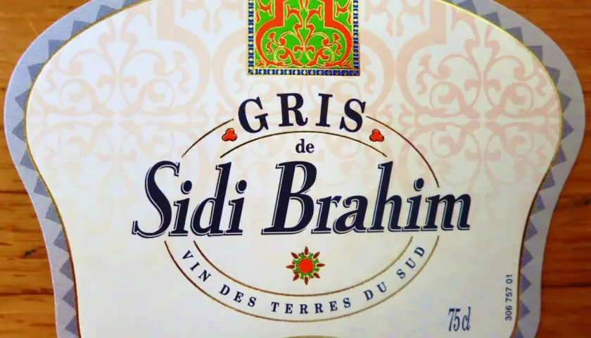 Étiquette de vin Sidi Brahim Gris, avec un motif floral vert et rouge en haut. Le texte "Sidi Brahim" est en gros caractères bleus.