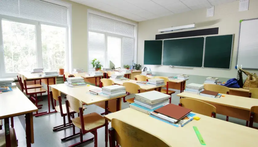 Puste ławki i stosy książek w sali lekcyjnej, jakby właśnie skończył się rok szkolny.
