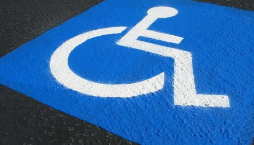 Niebieskie pole z białym symbolem wózka inwalidzkiego. Czy parking dla niepełnosprawnych jest płatny?