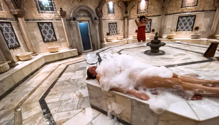 Kobieta w pianie w łaźni. Hammam co to? To tradycyjna turecka łaźnia parowa, miejsce relaksu i oczyszczenia.